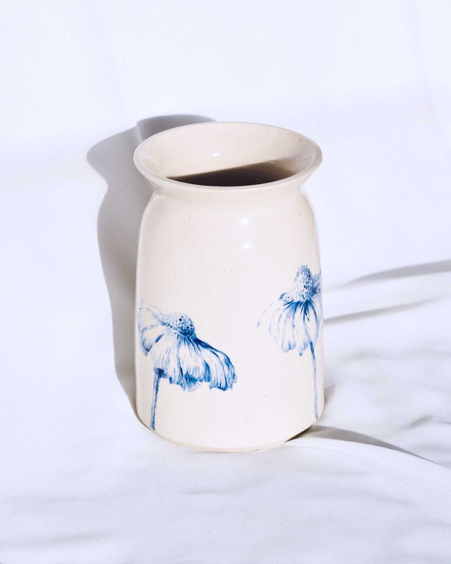 White ceramic vase with floral decoration on white background.