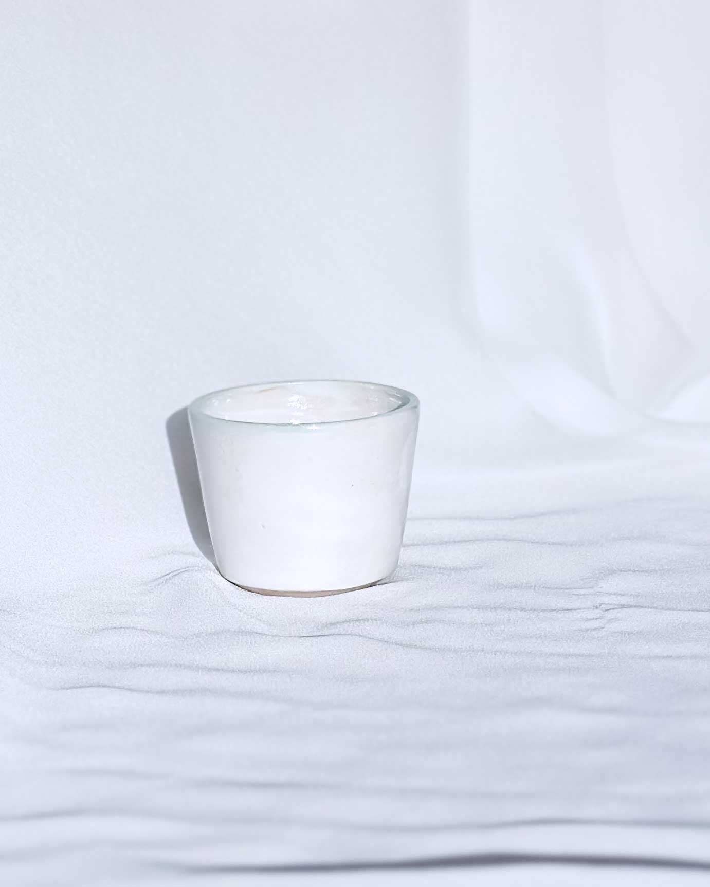 White ceramic cup on a white fabric background