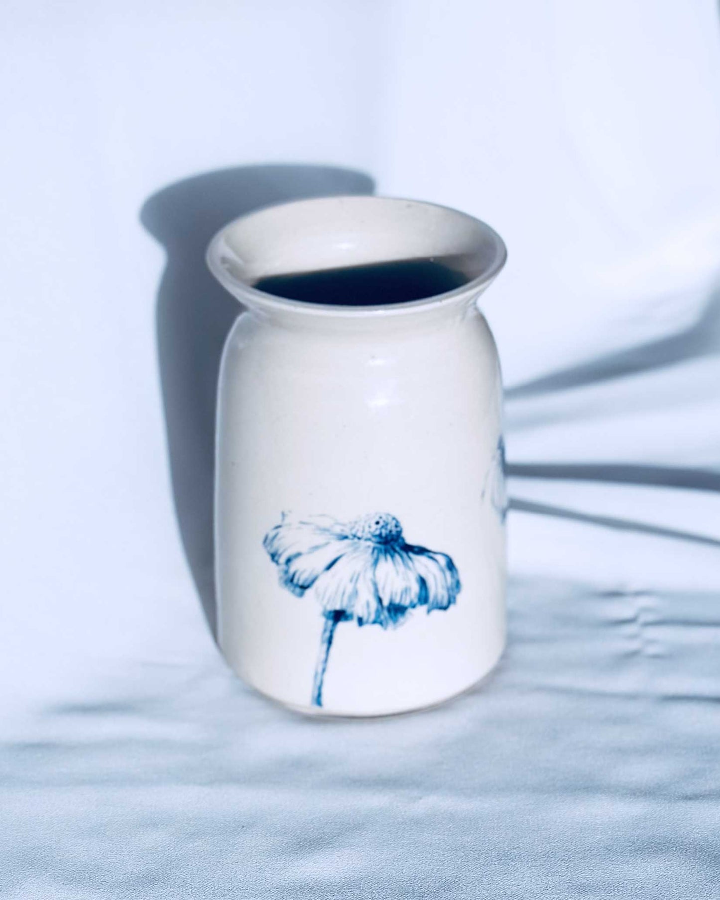 White ceramic vase with floral decoration on white background. 