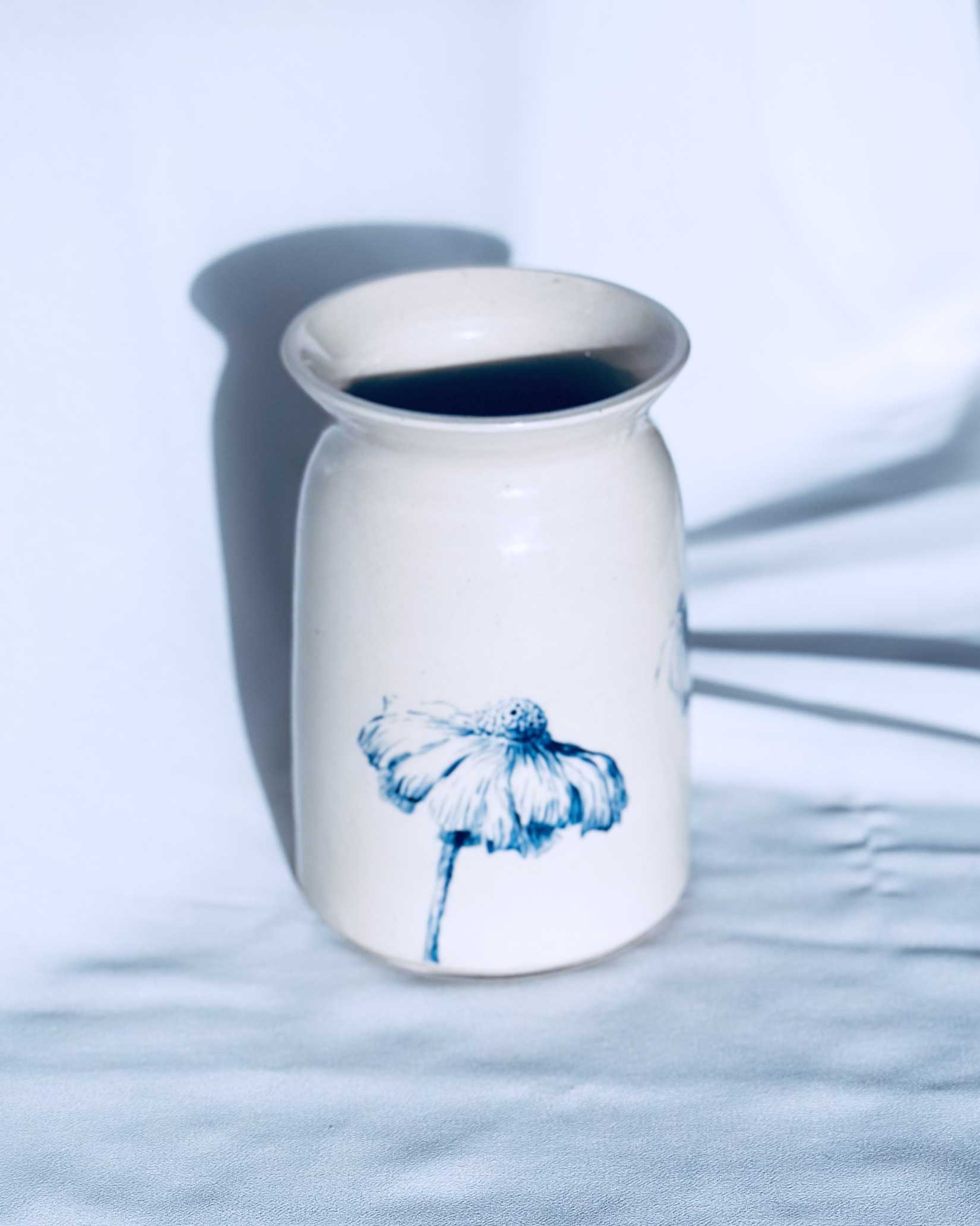 White ceramic vase with floral decoration on white background. 