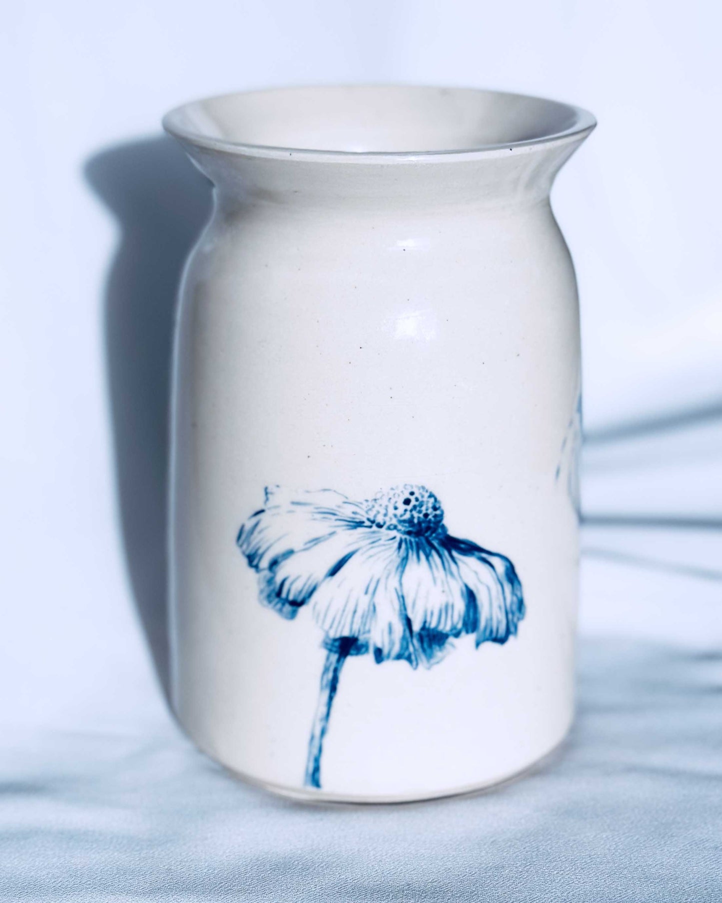 White ceramic vase with floral decoration on white background. 