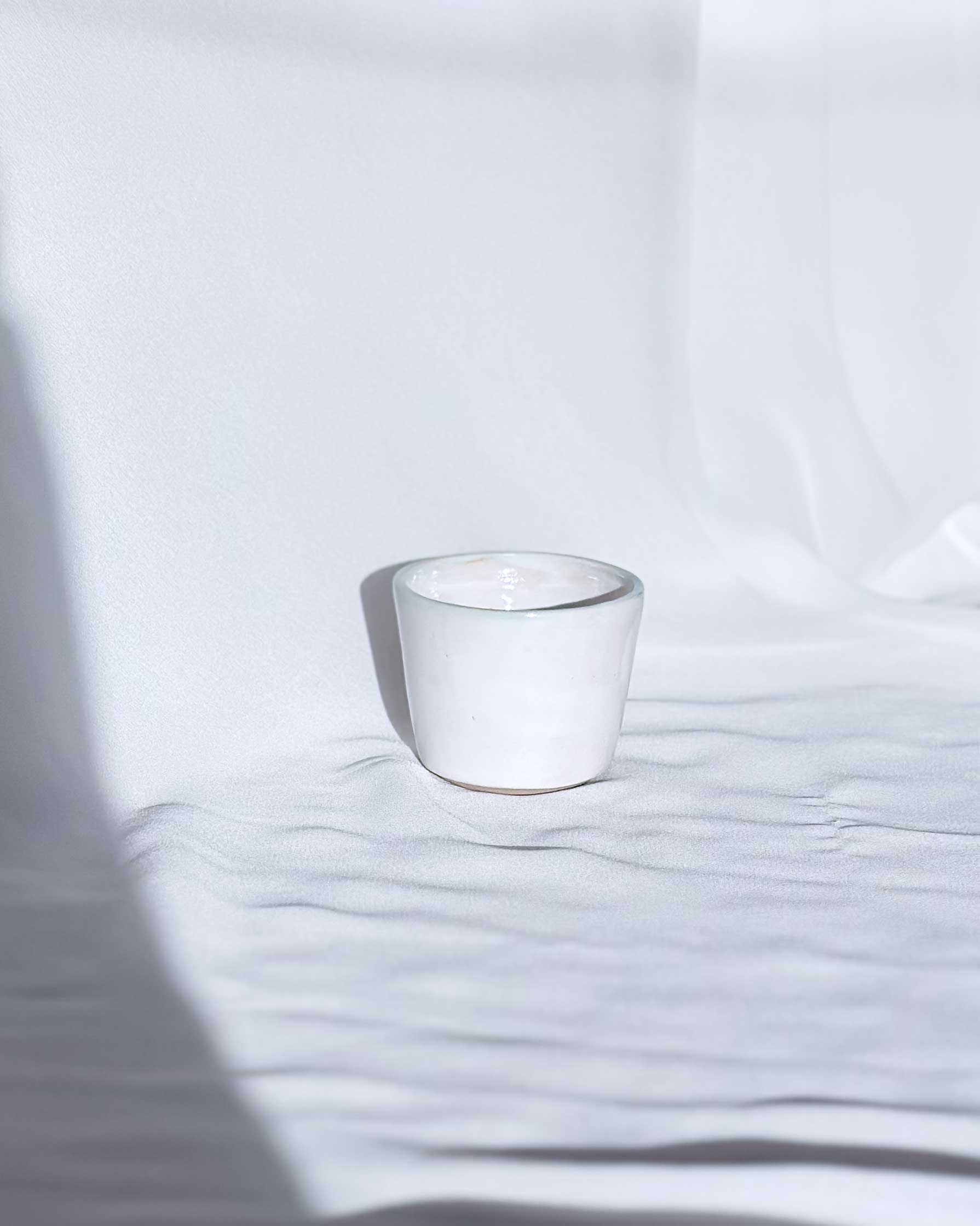 White ceramic cup on a white surface with soft shadows