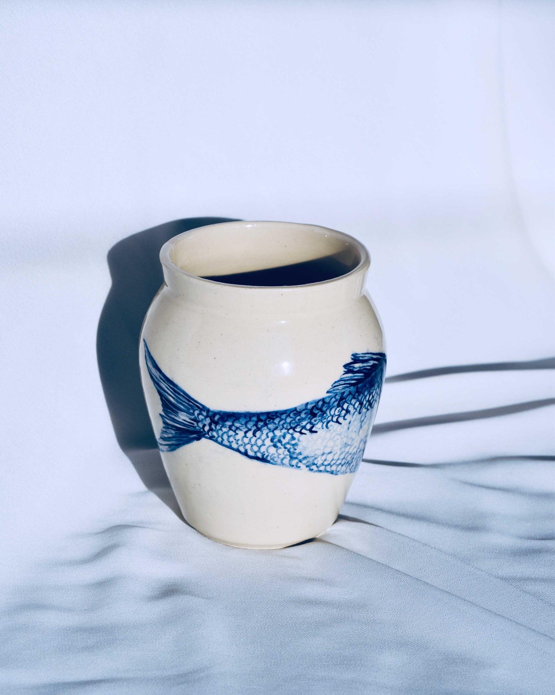 Ceramic vase with blue fish design on a white background