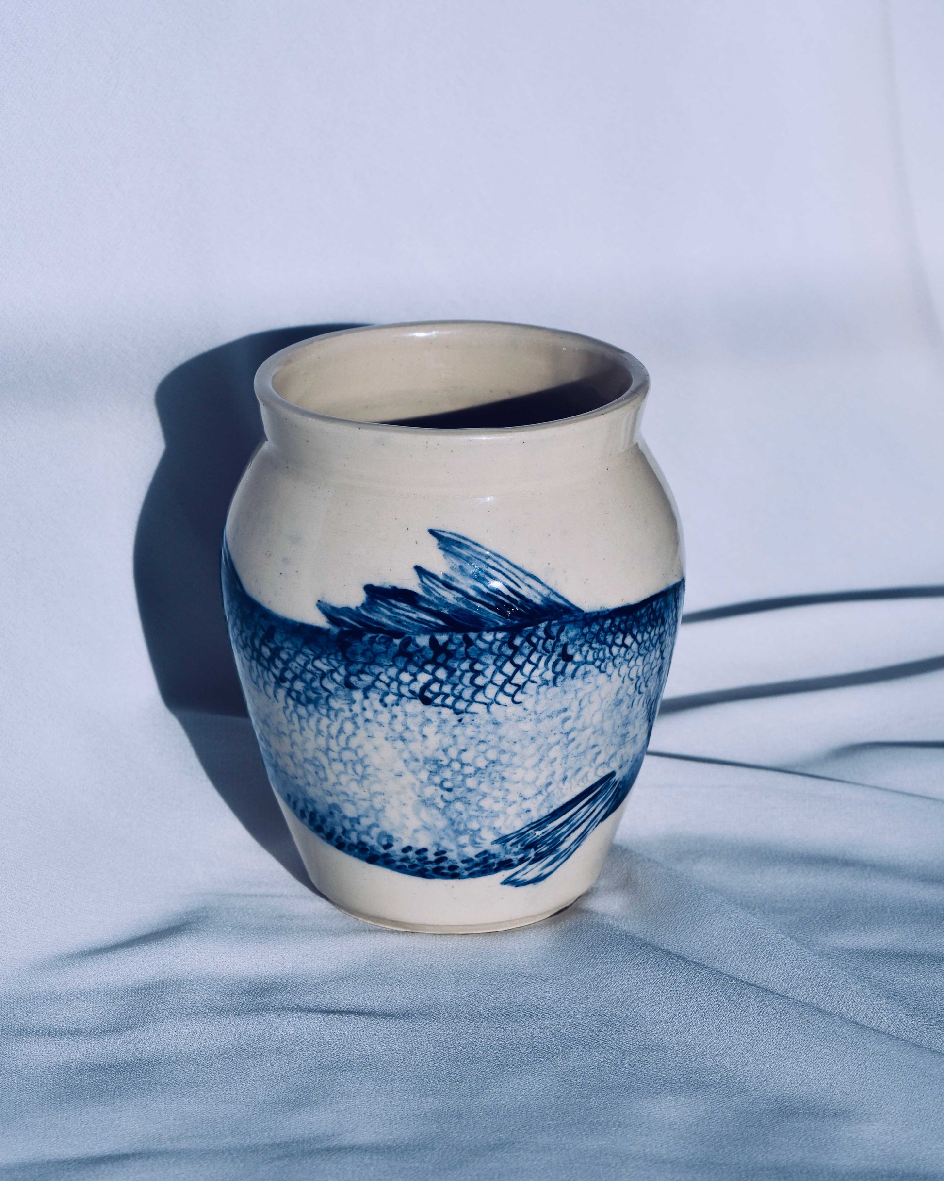 Ceramic vase with blue fish design on a white background