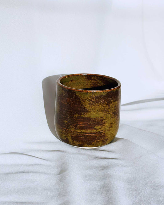 Brown ceramic cup on a white fabric background