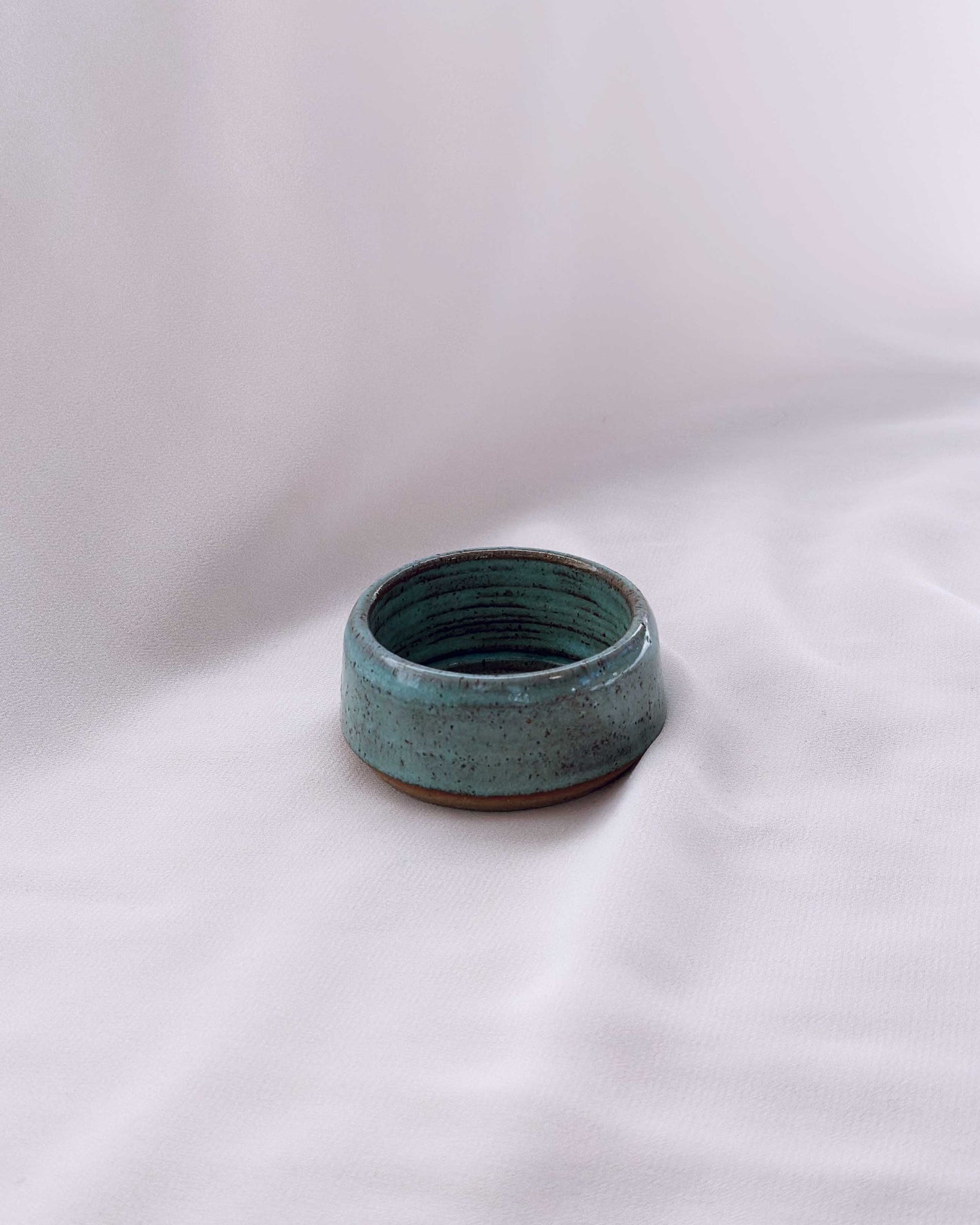 Small ceramic tea light holder with a textured surface on a white background