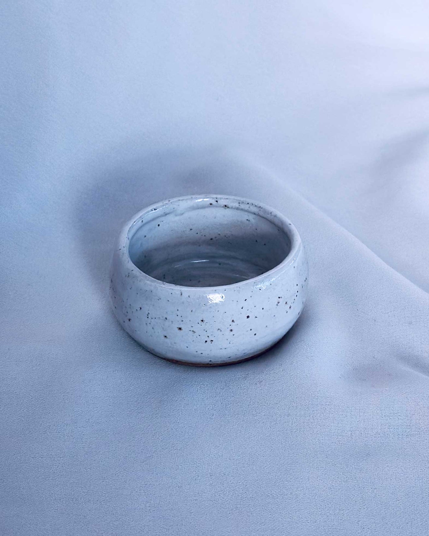 white ceramic tea light holder on a light blue fabric background
