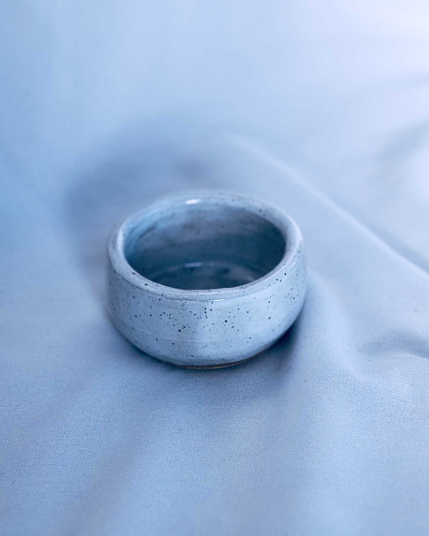 Small ceramic tea light holder on a light blue fabric background