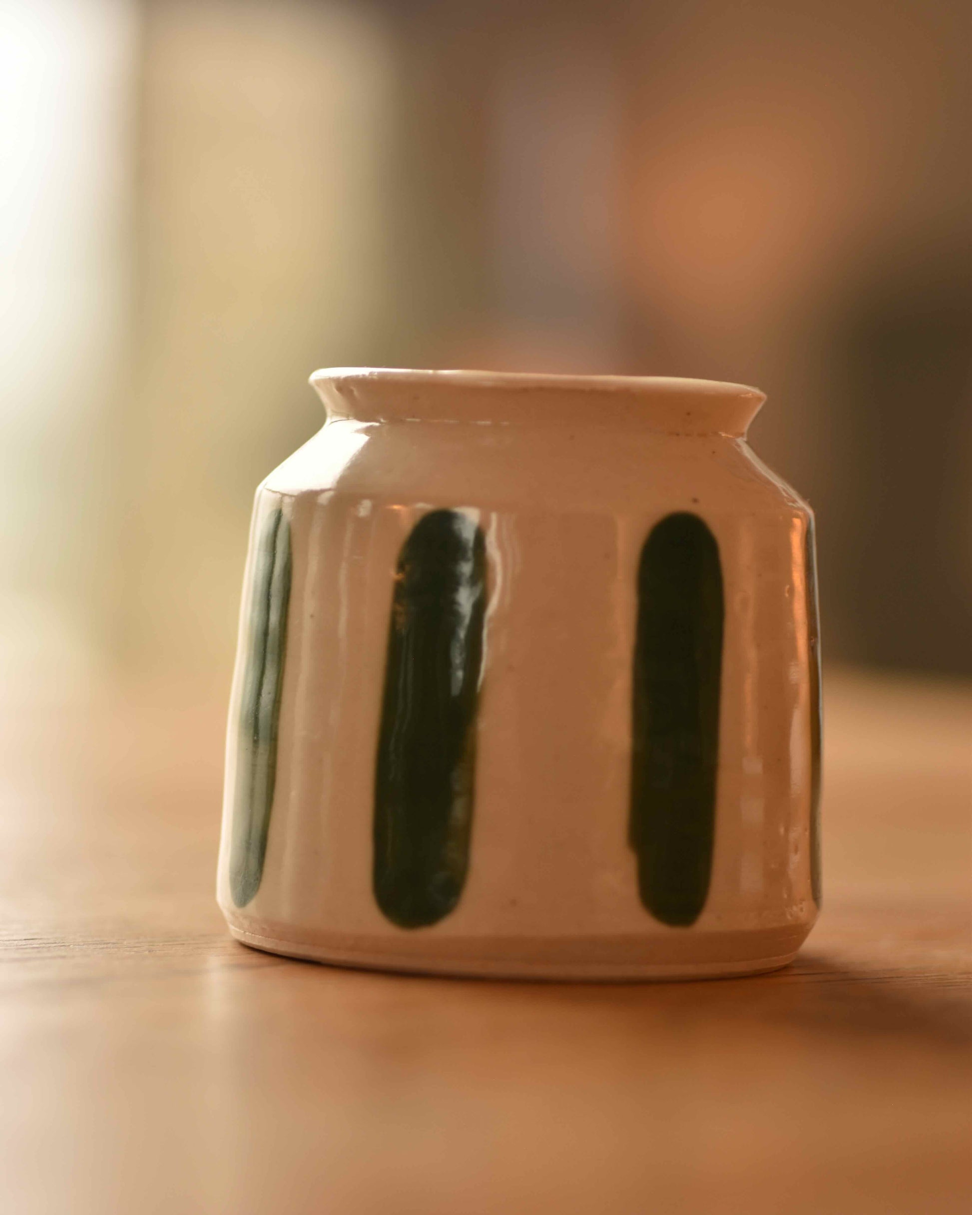 Ceramic jar with green accents on a wooden surface