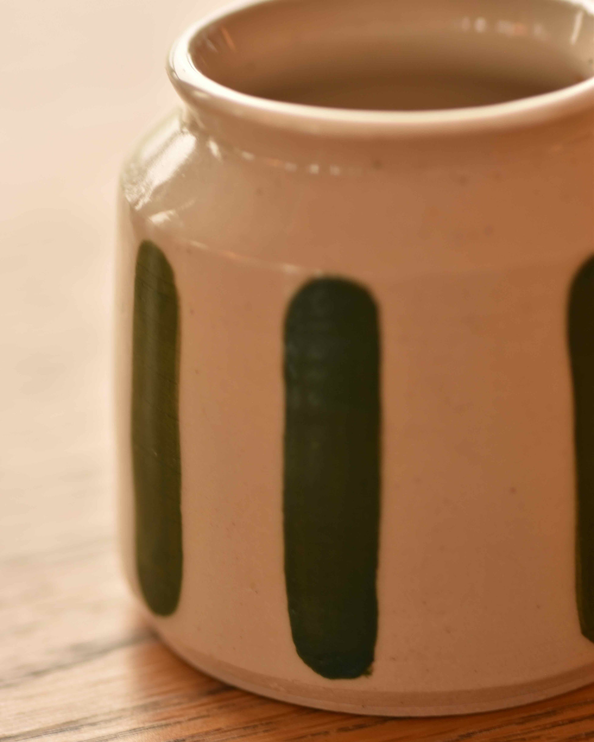 Ceramic vase with green stripes on a wooden surface
